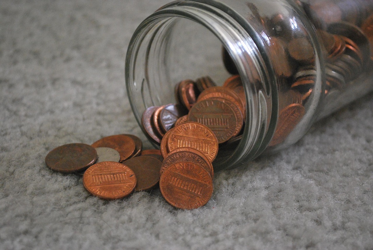 A glass jar filled with cash and coins labeled as savings on a wooden table.