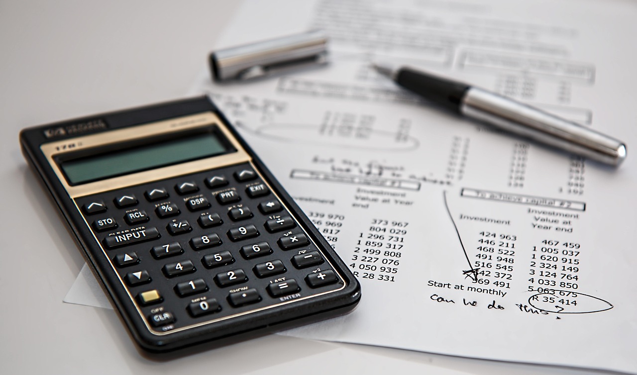 A desk setup with a calculator, notebook, and a pair of glasses, representing financial planning.