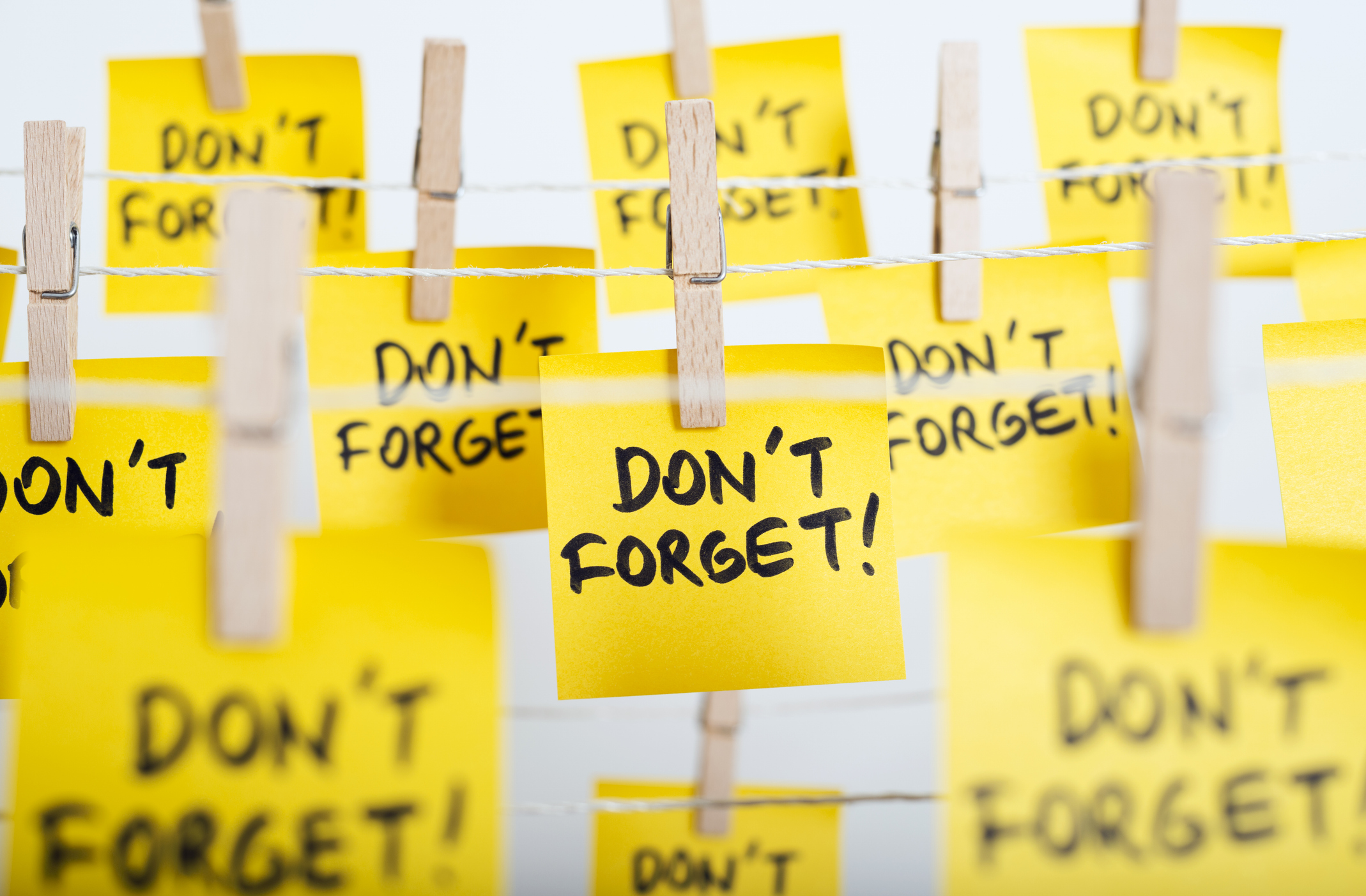 Adhesive note papers with 'don't forget!' message hanging on a rope.