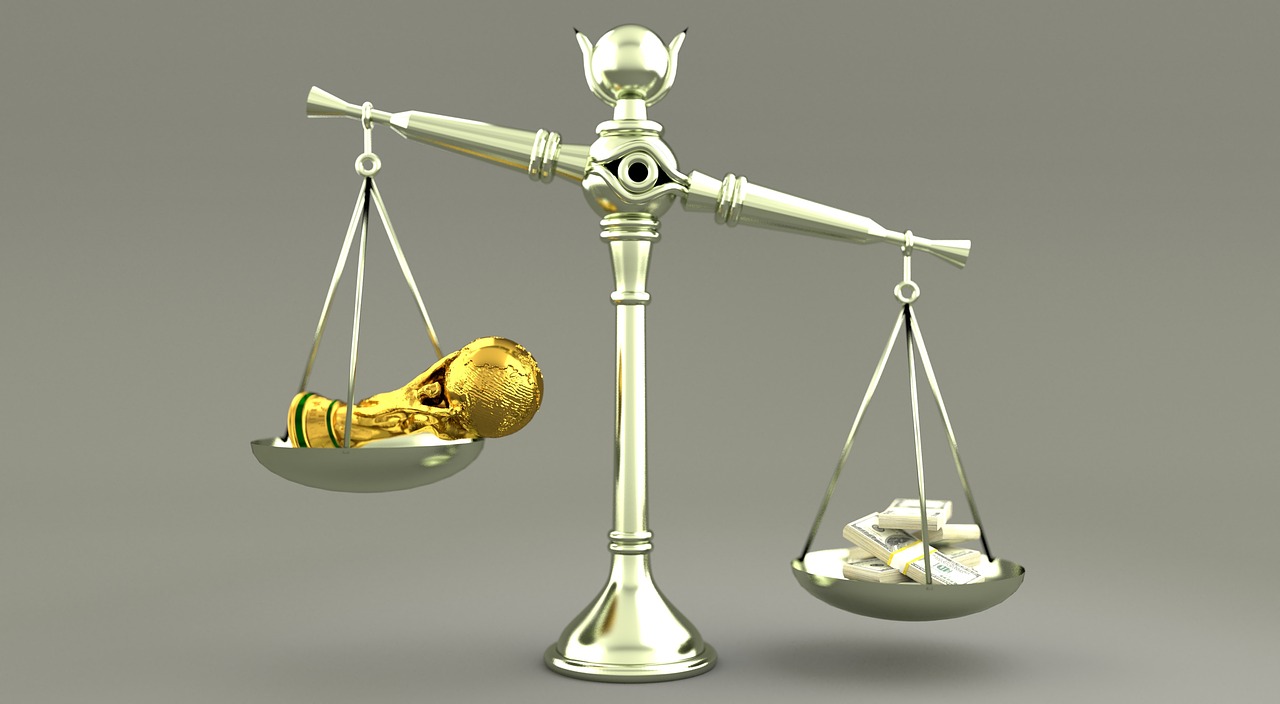 A set of brass scales balancing money and financial paperwork on a wooden desk.
